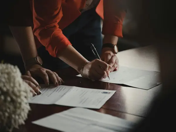 Hands signing USPS Form 1583 paperwork